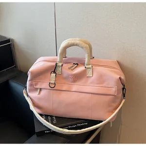 Grand sac de voyage rose élégant avec des sangles blanches sur un livre de design