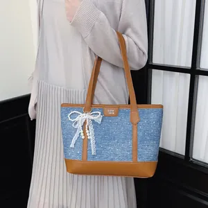 Sac cabas en jean bleu à la mode avec nœud en dentelle et perles porté à l'épaule