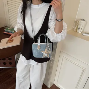 Close-up of mini denim crossbody bag featuring silver star charm and studs