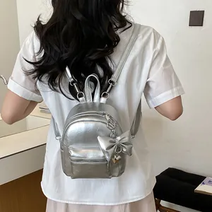 Modischer silberner Metallic-Mini-Rucksack mit Schleifenanhänger auf dem Rücken