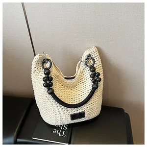 A detailed view of an elegant woven bucket bag featuring a unique black beaded handle