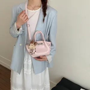 Modella che indossa una mini borsa a secchiello rosa con ciondolo a cane su un blazer blu