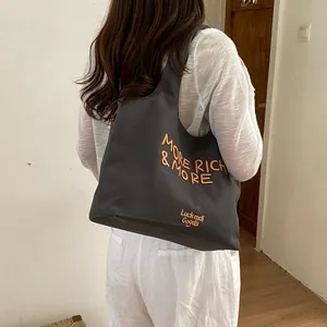 Vista trasera de estilo de vida de un gran bolso tote gris marengo con detalles de bordado naranja