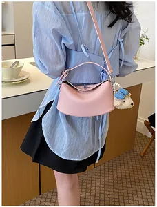 Detailed view of a pink lychee leather shoulder bag featuring a cute white bear charm
