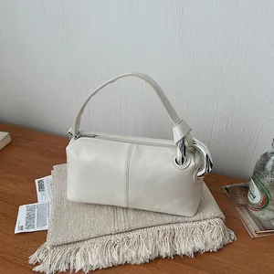 Close-up detail of a cream vintage pillow bag featuring chunky silver chain hardware on a wooden table