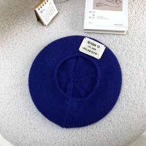 Top view of a cozy blue knitted beret hat featuring a unique letter patch detail