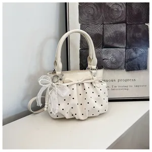 Elegant cream white polka dot pleated bucket bag with decorative bow and pearl charm detail.