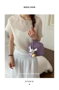 Detailaufnahme einer lila Lederhandtasche mit süßem Hasenanhänger an einem Model