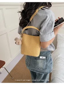 Elegant yellow woven bucket bag shown on a model for a vintage commuting look