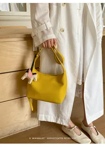 Minimalist yellow underarm shoulder bag with cute winged horse charm, chic commute style.