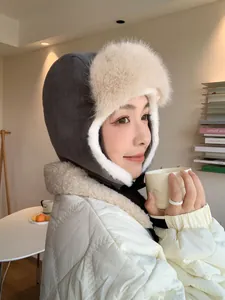 Asian woman wearing a warm grey corduroy trapper hat with soft white faux fur lining.