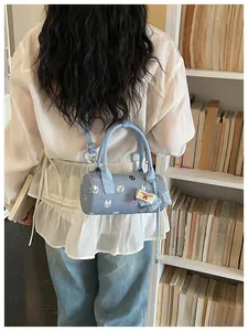 Stylish blue denim cylinder bag featuring cute cartoon cat prints and a cherry baby tag