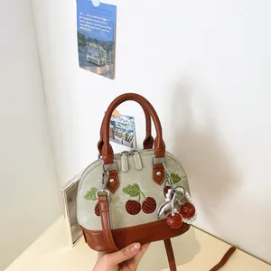 Vista detallada del bolso de diseño con bordado de cerezas y colgante de perlas fino