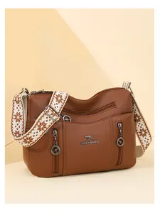 Detail view of a brown multi-pocket crossbody bag with elegant patterned wide strap