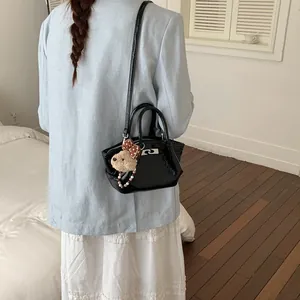 Dettaglio di borsa a mano nera lucida alla moda da donna con un grazioso ciondolo a orso