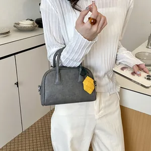 Detail of gray fashion pillow bag with yellow pineapple charm and top handles