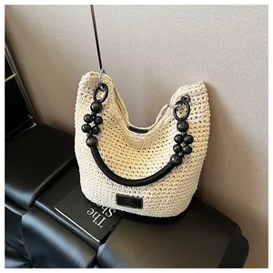 Detail of handwoven straw bucket bag featuring a unique black beaded strap handle