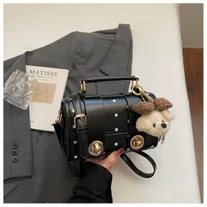 Close-up of vintage black polka dot crossbody bag with plush bear charm decoration