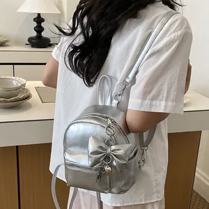 Detailansicht des silbernen Metallic-Minirucksacks mit Schleifendekor und Herzanhänger