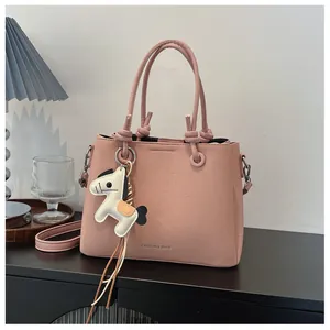 Close-up detail of the pink minimalist bucket bag featuring a white horse charm