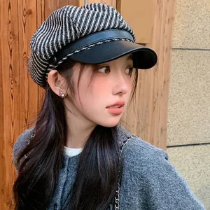 Stylish striped newsboy cap with black leather brim worn by a beautiful Asian female model