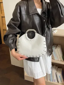 White crescent handbag with metal studs and ring handle, stylish crossbody bag