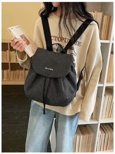 Casual black and white checkered small backpack for women shown in a daily lifestyle setting