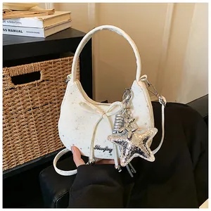 Detailed view of a white crescent handbag with bow and silver star balloon dog charm