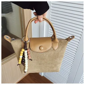 Détail d'un sac à main en daim kaki avec une breloque en perles décoratives pour femme