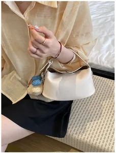 Detail view of a cream textured leather bucket bag with decorative bow and plush charms.