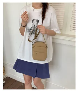 Khaki minimalist small square crossbody bag shown on a casual model for scale and daily style
