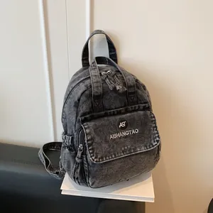 Detail eines gewaschenen Jeansrucksacks mit AST AISHANGTAO-Markenlogo und Mehrschichtdesign