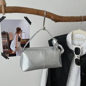Stylish silver retro pillow handbag with metallic finish hanging on a rustic wooden branch