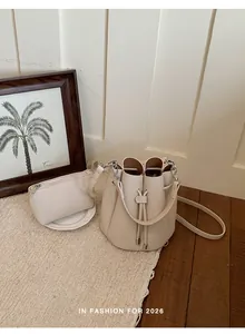 Fashionable cream drawstring bucket bag and matching pouch set in lifestyle setting