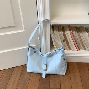 Stylish light blue underarm tote bag displayed against a minimalist home background.