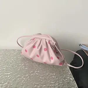 Detail view of a pink pouch bag with dark pink polka dots and minimalist pleated design.