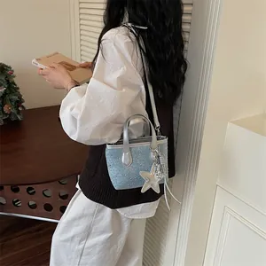 Stylish light blue denim bucket bag with rhinestones and a silver star charm for women.