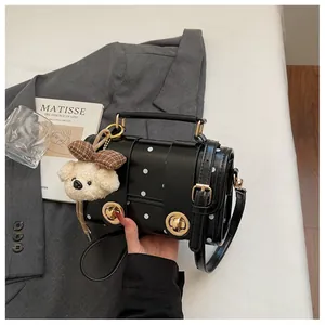 Stylish black polka dot handbag detail held by hand with cute bear keychain accessory