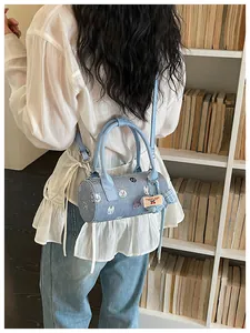 Detailed view of denim cylinder bag with cat patches worn by model in a library