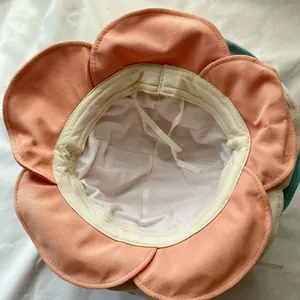 Close-up detail showing the white inner lining and ties of a coral flower sun hat.