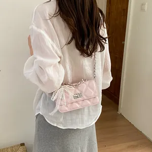 Detailed view of a stylish pink quilted crossbody bag with decorative lace and pearl bow accent