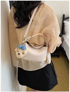 Elegant cream bucket bag with cute bear charm and pearl strap worn by a woman