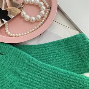 Close-up macro detail of vibrant green ribbed knit gloves in a lifestyle setting with pearls