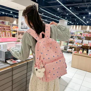Student pink backpack with colorful star patterns and plush bear charm shown on model