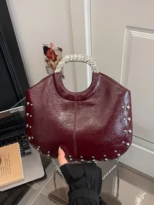Elegant burgundy glossy studded handbag with a silver metal handle and detachable chain strap