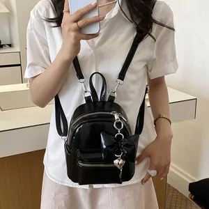 Detailansicht eines schwarzen Mini-Rucksacks aus Lackleder mit Schleife und Herz