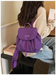 Purple grid pattern mini backpack worn by model in a casual indoor lifestyle setting