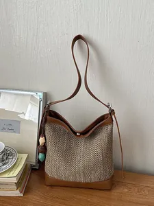 Large capacity straw woven bucket bag with elegant brown leather trim for summer.