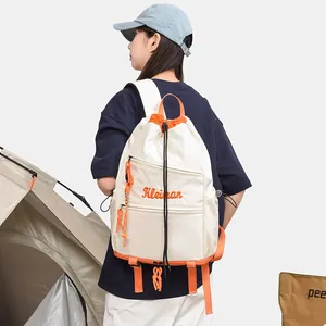 Vue arrière d'un sac à dos blanc et orange au design de niche dans un décor de camping