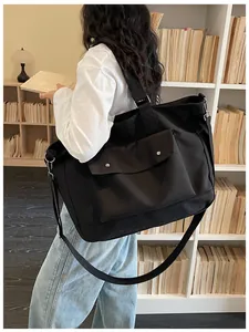 Large black canvas tote bag carried by a model in a cozy library lifestyle setting.
